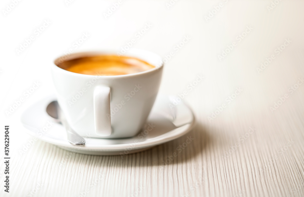 Hot coffee in white cup, beautiful texture of table. Selected focus on cup handle, empty space for text and design. Natural morning light.