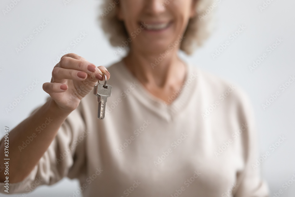 Close up smiling mature woman holding house keys, satisfied middle aged female customer buying dwelling, apartment, making successful real estate deal, purchasing property, elderly mortgage program Close up smiling mature woman holding house keys, satisfied middle aged female customer buying dwelling, apartment, making successful real estate deal, purchasing property, elderly mortgage program