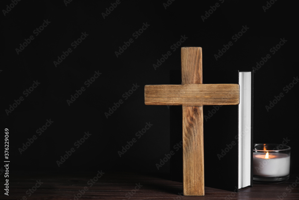 Cross, Bible and burning candle on wooden table, space for text. Christian religion
