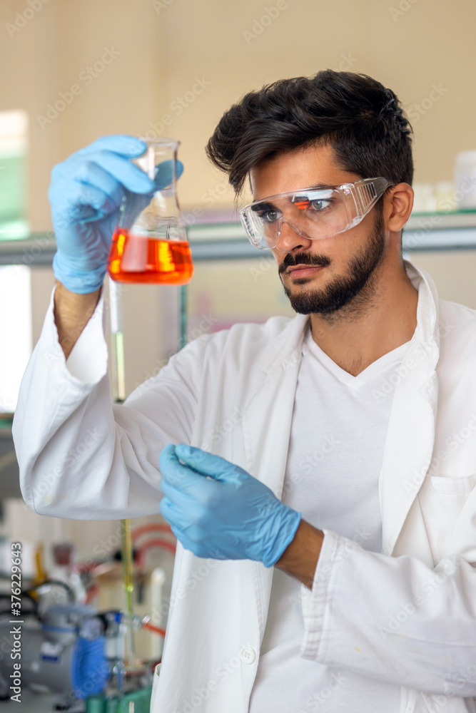 Research scientist looking at reaction in test tube in laboratory Research scientist looking at reaction in test tube in laboratory