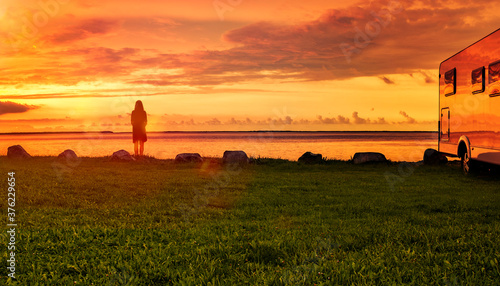 Frau mit Wohnmobil am Strand bei Sonnenuntergang