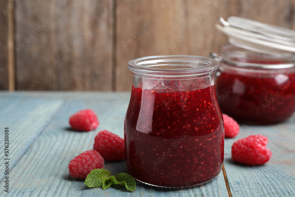 Delicious jam and fresh raspberries on light blue wooden table Delicious jam and fresh raspberries on light blue wooden table
