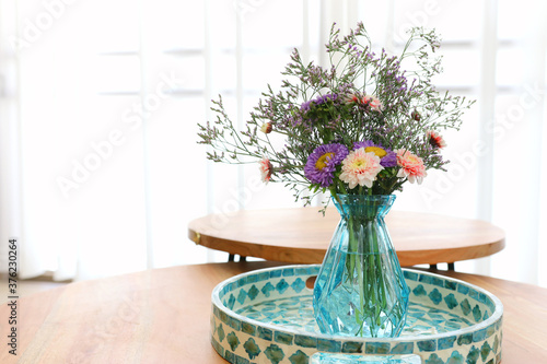 Fototapeta Naklejka Na Ścianę i Meble -  bouquet of colorful field flowers in the glass blue vase over wooden table