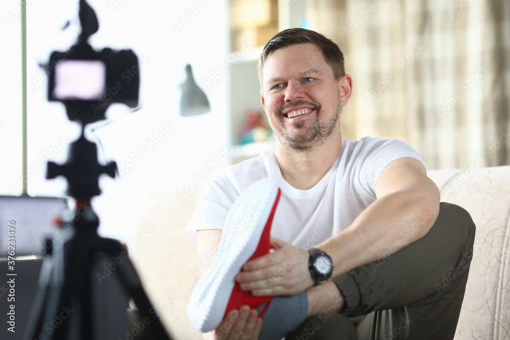 Fototapeta premium Male blogger makes video review on camera on topic of sneakers. Online shopping concept