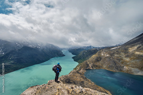 young hiker with backpack enjoy the wiev of besseggen ridge, gjende lake in the Jotunheimen national park norawy mountains