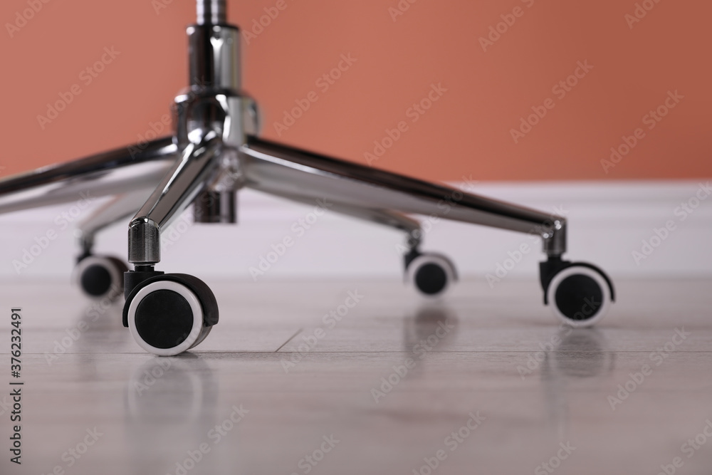 Modern office chair with wheels on wooden floor, closeup Modern office chair with wheels on wooden floor, closeup
