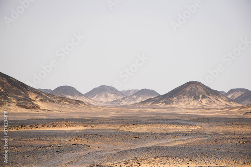 landscape black rock desert off egypt, high mountains with rocks and sand. Scenic volcanic landscape in desolate nature. Extreme travel destination. Travel background. 