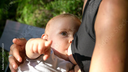 A cute baby at breastfeeding in nature. A baby pointing to the camera photo