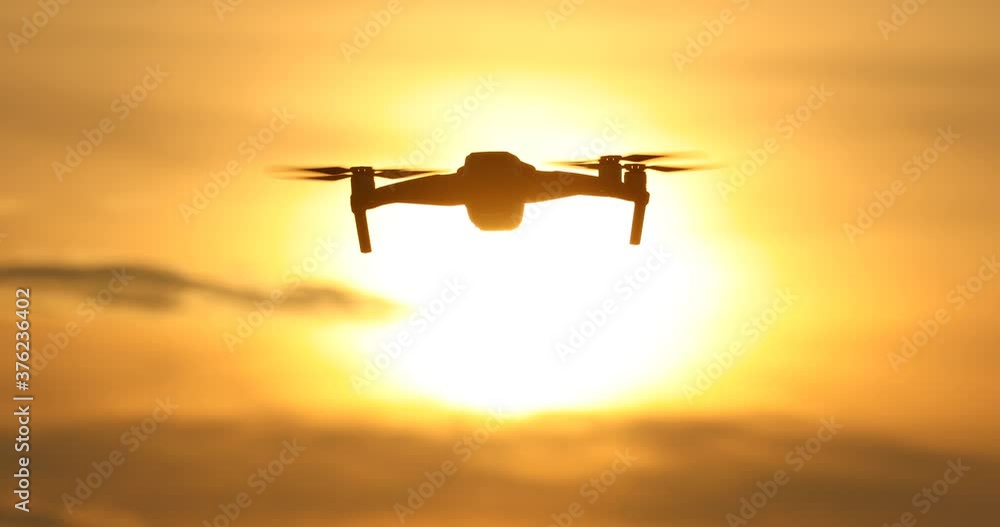 A silhouette Quadrocopter flies at sunset.sunset, drone in the sunset sky,A drone taking pictures of aerial views A silhouette Quadrocopter flies at sunset.sunset, drone in the sunset sky,A drone taking pictures of aerial views