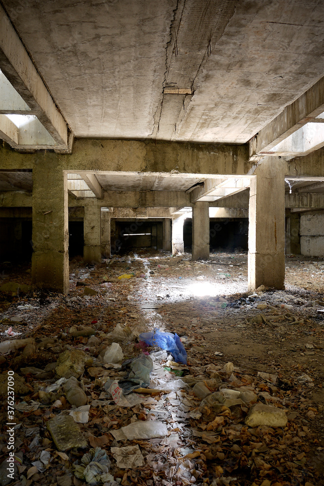 Fototapeta premium Unfinished and abandoned concrete and brick building. Unfinished construction with harsh sun light and shades.