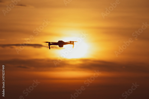 A silhouette of a drone flying in a beautiful sunset  drone in the sunset sky A drone taking pictures of aerial views