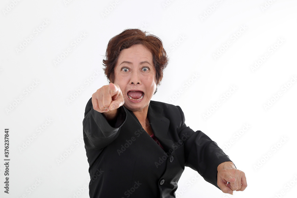 Elderly asian Chinese female on white background wearing black suit point at camera angry furious mouth open shout Elderly asian Chinese female on white background wearing black suit point at camera angry furious mouth open shout