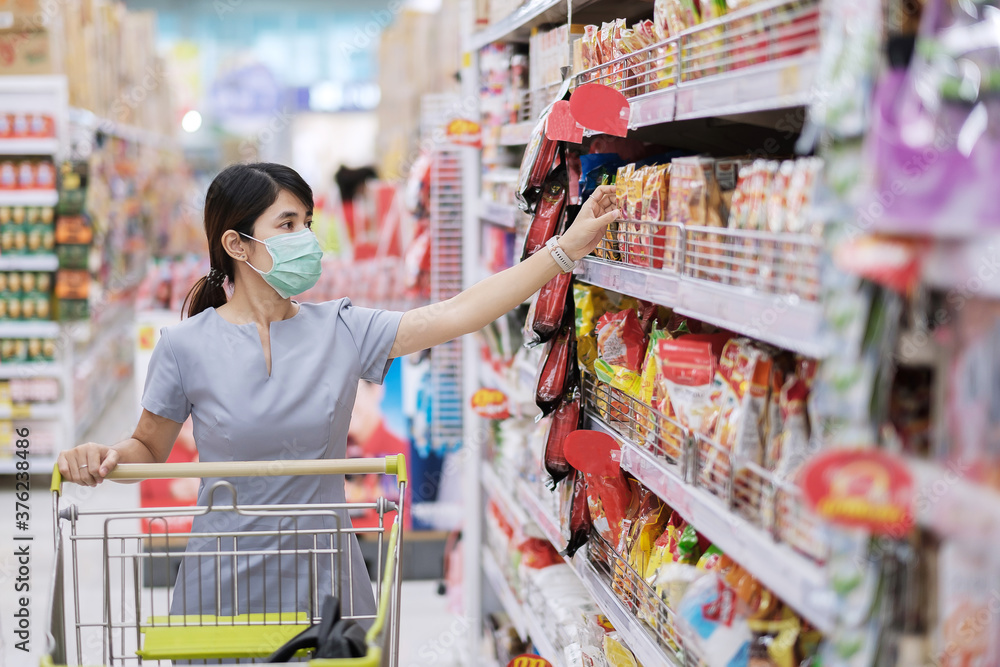 Young woman wearing protective face mask and shopping in grocery or department store protect coronavirus inflection. social distancing, new normal and life under covid-19 pandemic Young woman wearing protective face mask and shopping in grocery or department store protect coronavirus inflection. social distancing, new normal and life under covid-19 pandemic