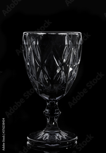 Black faceted wine glass on black background, close up