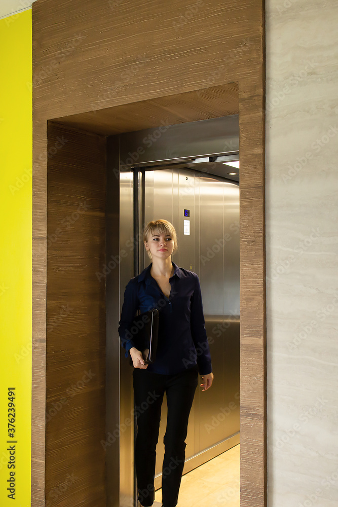 Beautiful business blonde comes out of elevator in office Beautiful business blonde comes out of elevator in office