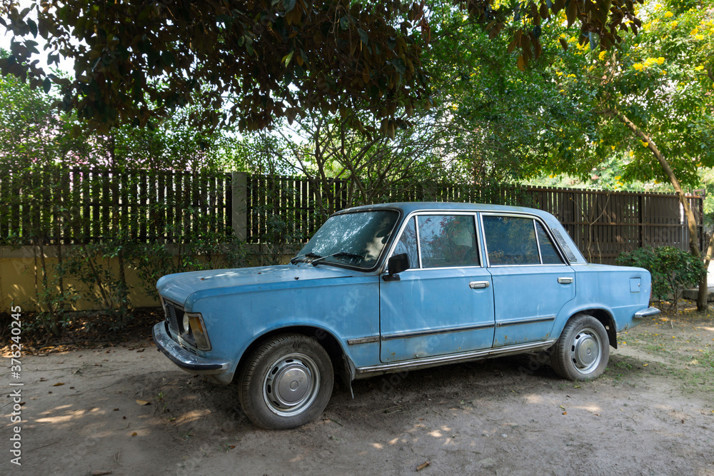 The old, abandoned blue car in a garden The old, abandoned blue car in a garden