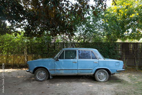 The old, abandoned blue car in a garden © uppichaya