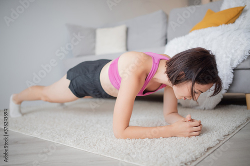 Woman training home, performs exercises on abdominal plank muscles