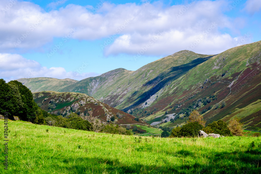 Rolling fells and valley in the Lake District with green fields in the summertime