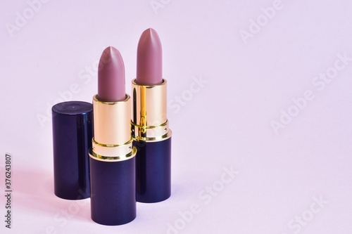 Pink matte lipsticks isolated on a pink background. Beauty industry product concept. Glamorous makeup accessory close up on pink. Cosmetology, elegance attribute. 