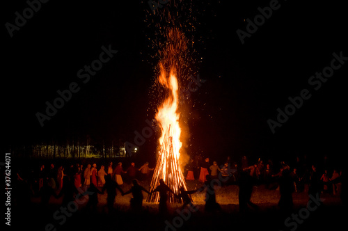 People dance at night around a big fire