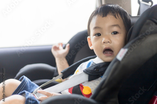 Adorable Asian kid boy (Toddler age 1-year-old) Protection Sitting in the Car Seat with Safety Belt Locked.