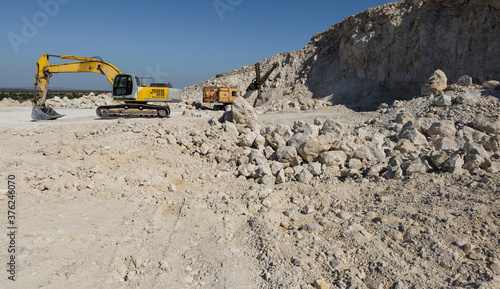Fotografie A large yellow tracked excavator is mining rock in a quarry.