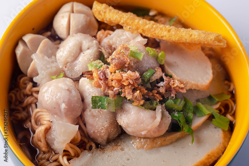 Instant noodles with fish kiew, pork balls and wonton plates. Thai food on a white background.