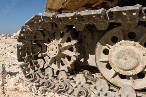 A close-up of the tracks of a heavy large excavator in a mining quarry.