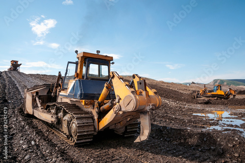 Bulldozers in mountainous wooded areas, layer by layer, remove mountain soil from the surface and shovel it to the side.