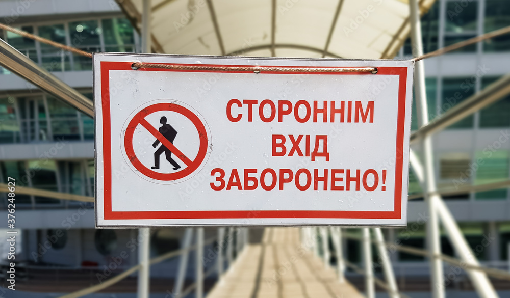Obraz premium Warning sign No unauthorized entry written in red text in Ukrainian on a white rectangular table. The sign prohibits the passage of strangers.
