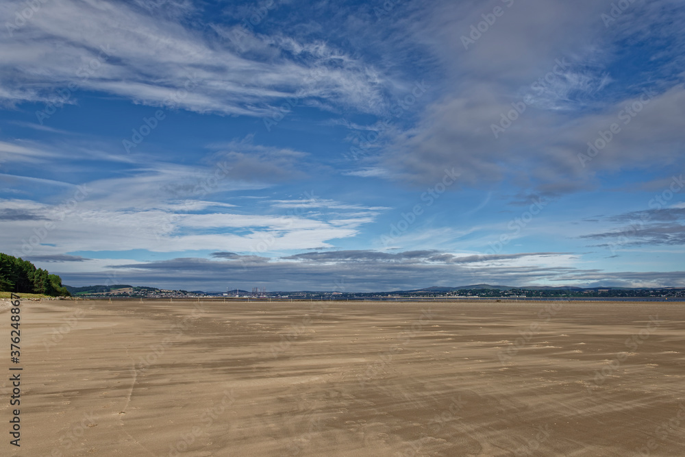 The Wide sandy gently shelving beach of the Tay estuary with Dundee and the Coast of Angus under the sunny light of an early morning in August. The Wide sandy gently shelving beach of the Tay estuary with Dundee and the Coast of Angus under the sunny light of an early morning in August.