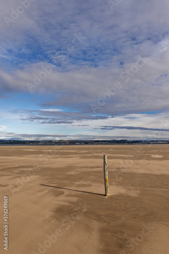 An upright Wooden Post or Marker on the gently shelving beach at Tentsmuir Point on the south side of the Tay Estuary.