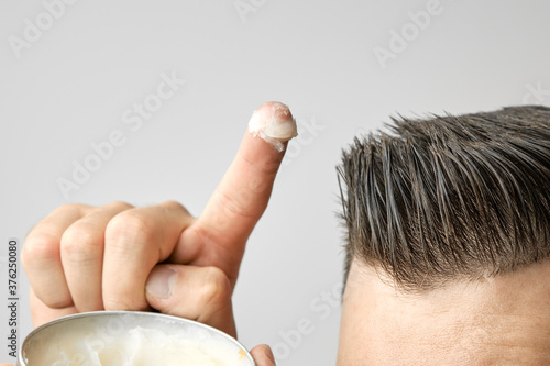 Bild auf Leinwand Man applying a clay, pomade, wax, gel or mousse from round metal box for styling his hair after barbershop hair cut