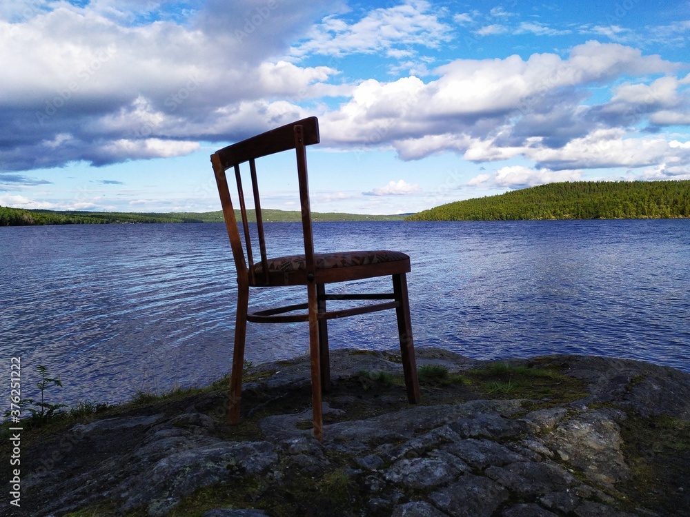 Old wooden chair on a high stone lake shire in the forest