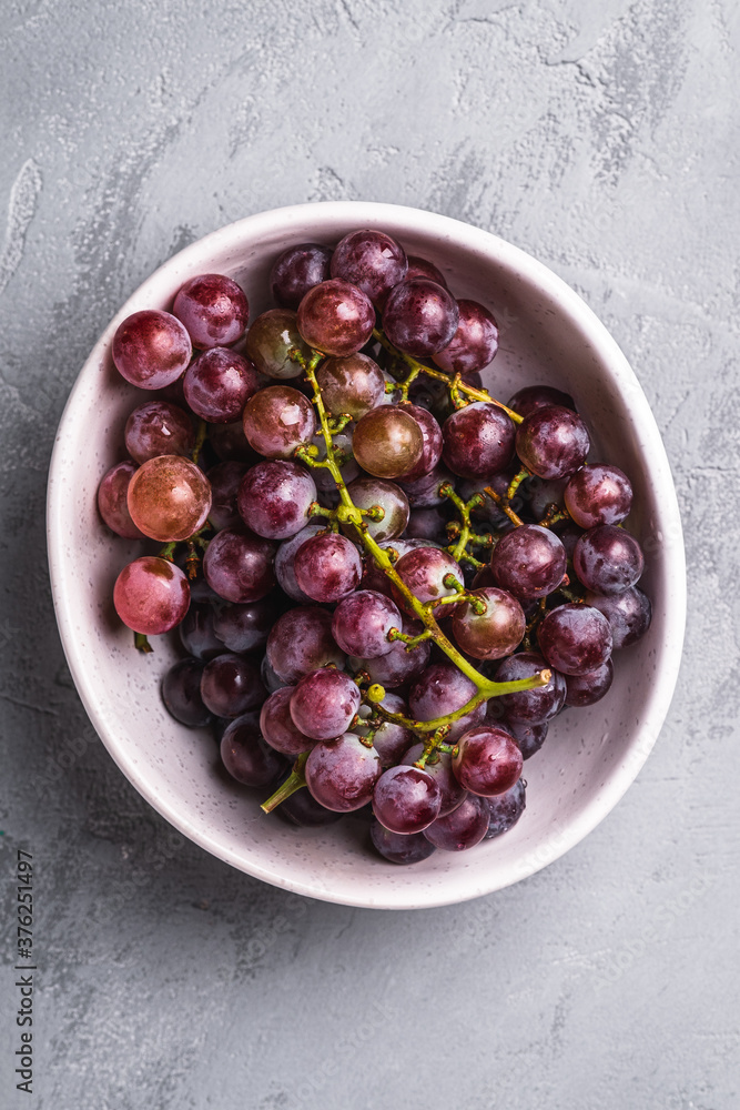 Fresh ripe grape berries in bowl on stone concrete background, top view Fresh ripe grape berries in bowl on stone concrete background, top view