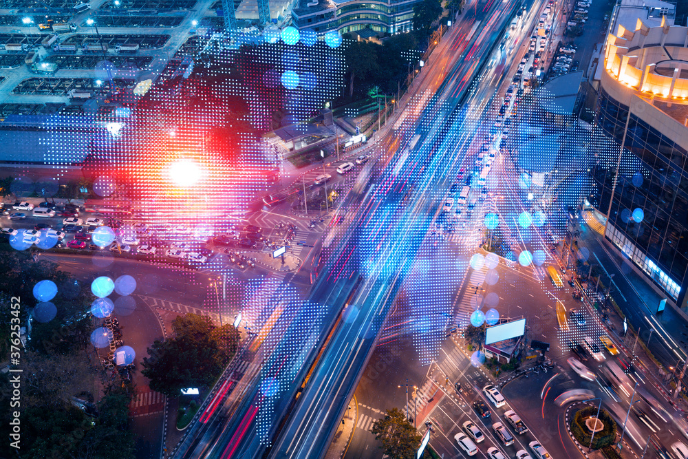 Obraz premium World planet Earth map hologram on aerial view of road, busy urban traffic highway at night. Junction network of transportation infrastructure. The concept of success in logistics business.