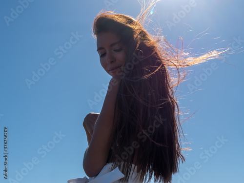 dark-skinned woman in white shorts with long hair poses for photographer on river bank against background of waves