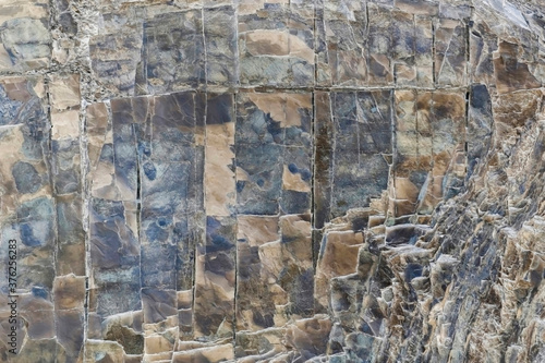 Rough texture of mountain wild stone. Marble. Granite. Stone abstraction. Mountain stone. The rough surface of an ancient mountain. Grunge texture. Laminated surface. Abstract grunge background.