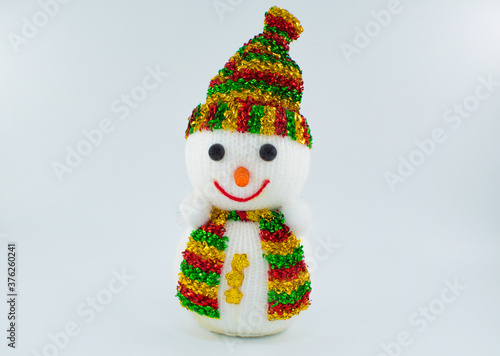 Cristmas soft toy of a snowman in a multicolored scarf and hat.