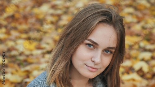 Portrait of a young and beautiful girl against a background of yellow leaves. Face close up.