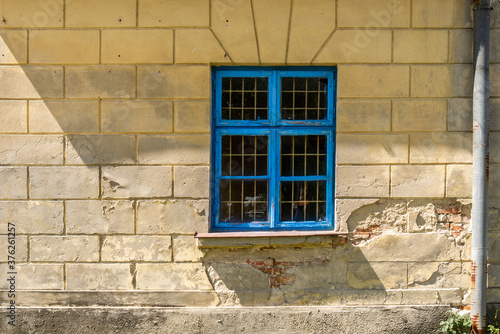 Window with blue frame and lattice in old building wall (former hospital). Architectonic details of abandoned buildings. Maciejowice, Poland, Europe. photo