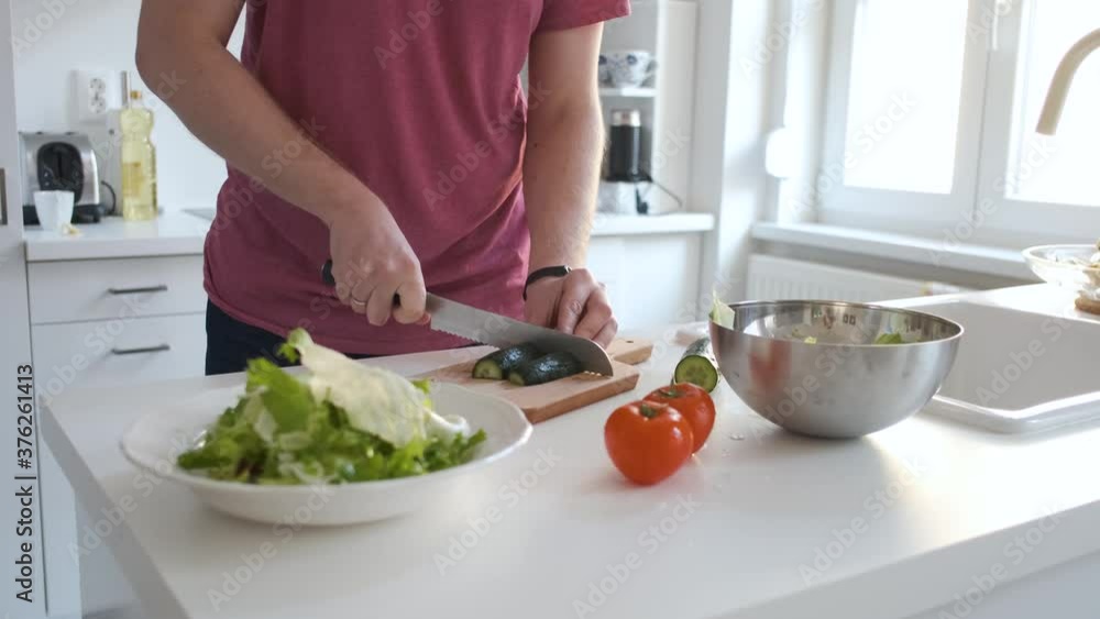 close-up of a man cuts a cucumber for salad close-up of a man cuts a cucumber for salad