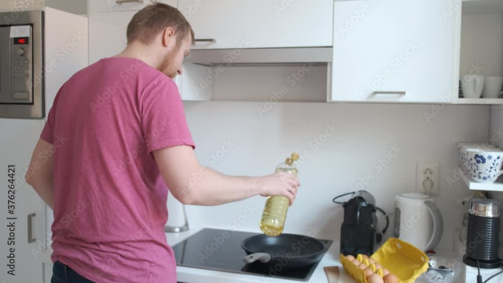 Caucasian man preparing breakfast scrambled eggs in a white kitchen Caucasian man preparing breakfast scrambled eggs in a white kitchen