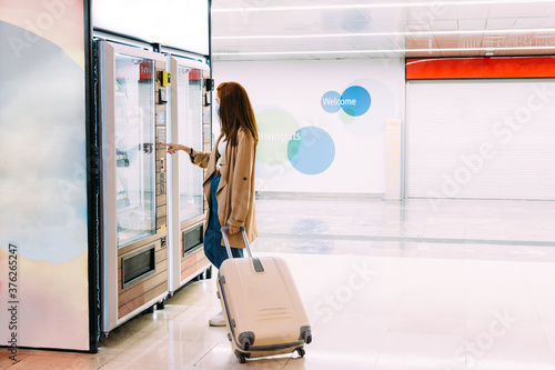 Obraz na plátně woman with a face mask uses the vending machine to buy a snack