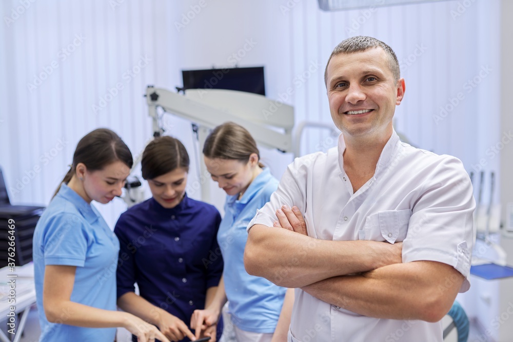 Portrait of male doctor dentist and female interns in the dental office