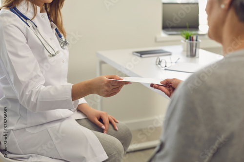 The doctor gives the patient a prescription while sitting at the workplace in the office of a medical clinic.