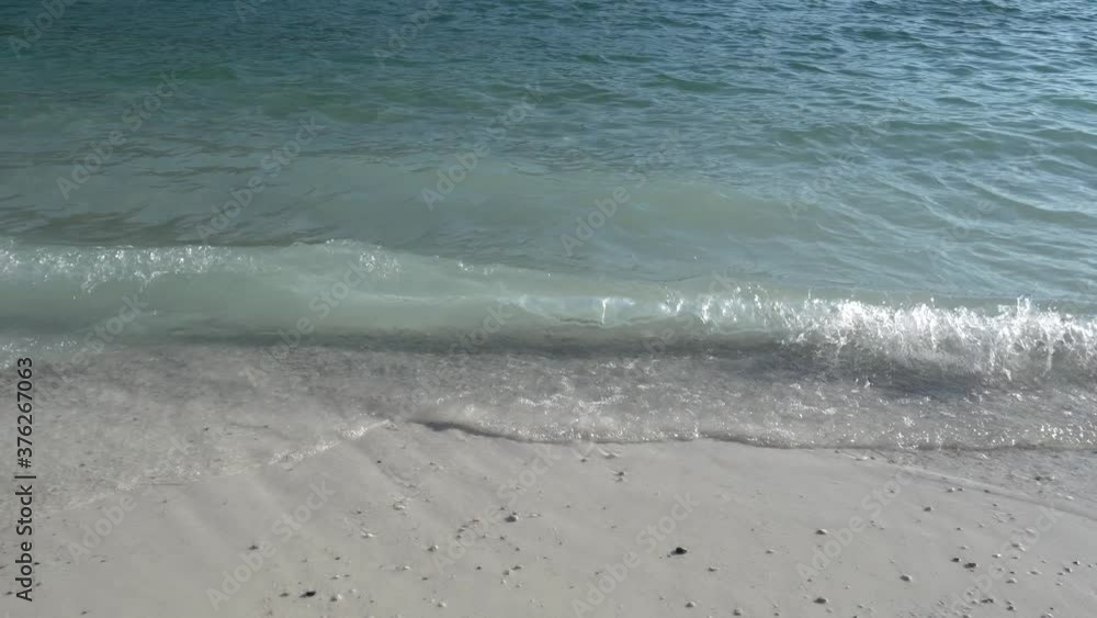 Aegean, turquoise sea wave rolls on the white sandy beach. The snow-white foam on the waves contrasts with the blue of the water and white sand. Summer sea background Aegean, turquoise sea wave rolls on the white sandy beach. The snow-white foam on the waves contrasts with the blue of the water and white sand. Summer sea background