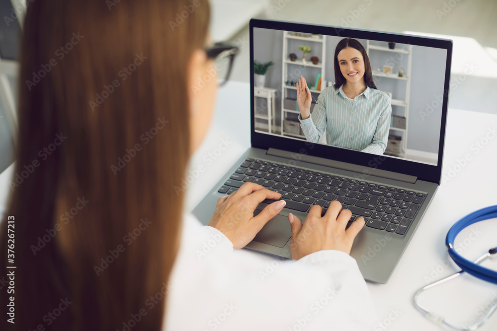 Video call to doctor online. Woman patient greets doctor of medical clinic in laptop monitor video call at home.