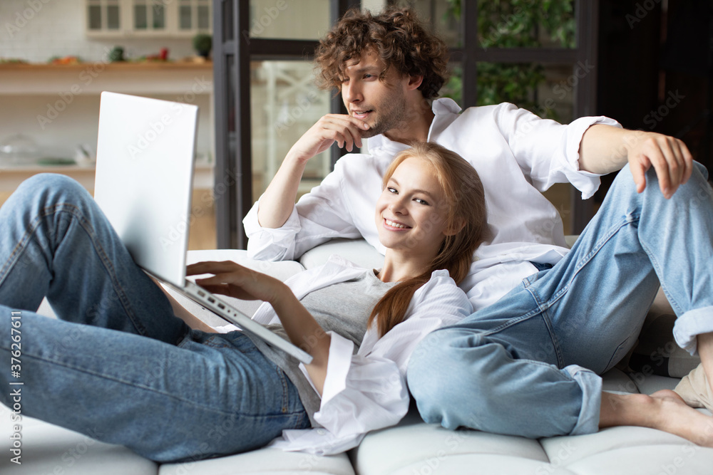 Happy couple on couch with laptop. Happy couple on couch with laptop.